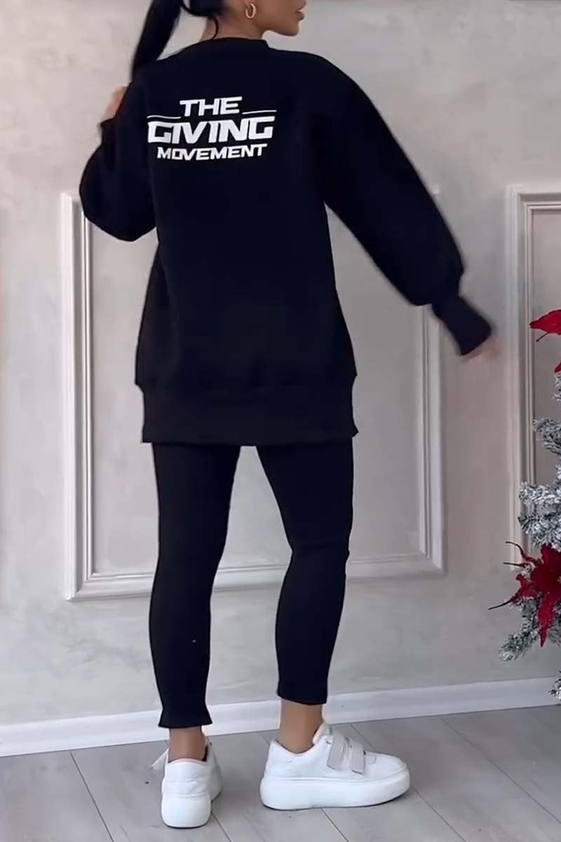 Black long-sleeved sweater with "THE GIVING MOVEMENT" print, paired with black leggings and white sneakers.