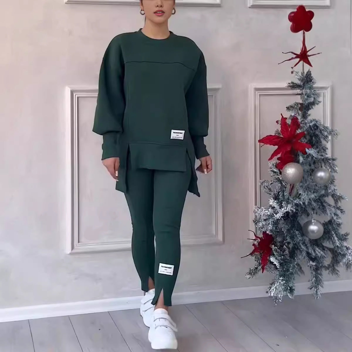 Long-sleeved dark green sweater with side slits paired with matching leggings, worn with white sneakers.