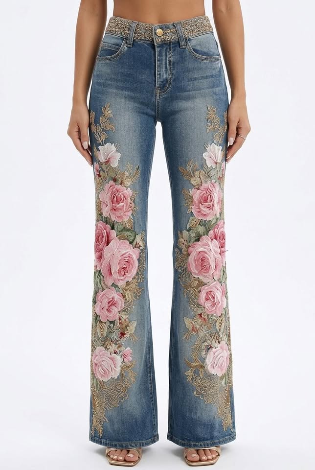 Faux denim flared trousers with pink floral embroidery and a mid-rise waist, featuring a gold-tone patterned waistband.